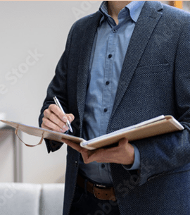 Man in business casual attire writing in an open binder to illustrate credit monitoring and home financial security.