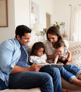 Family of four relaxed on a couch, reading a book together about securing financial information with tips on password management, phishing scams, cybersecurity, and preventing financial fraud.