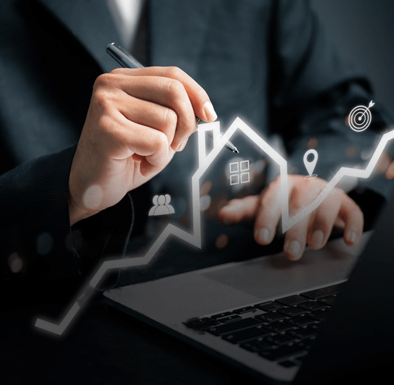 Man in a suit at a computer holding a pen with a digitally imposed house outline on an increasing graph line. The Ultimate Guide to Home Finance Security for New Homeowners.